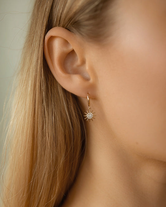Close-up of a person wearing a gold earring with a star design.