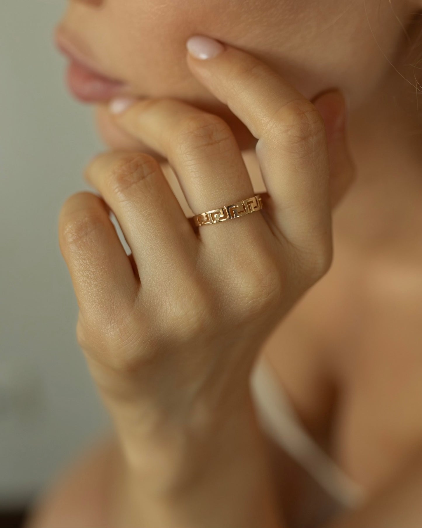 Close-up of a hand wearing a gold ring with a blurred background