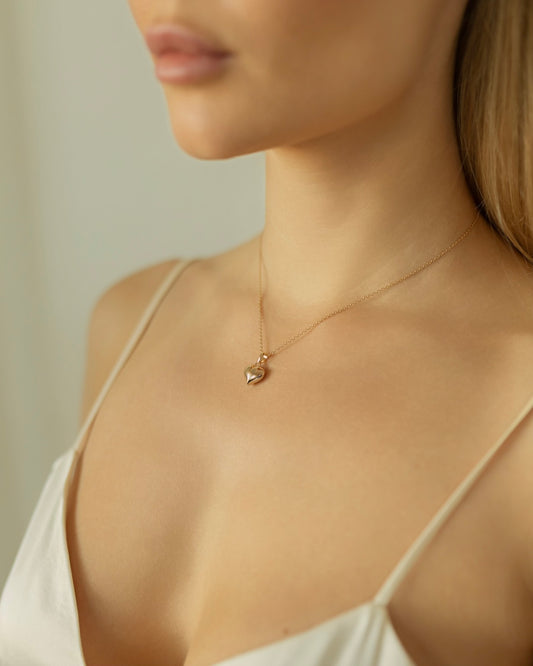 Necklace with a heart-shaped pendant worn by a model against a neutral background