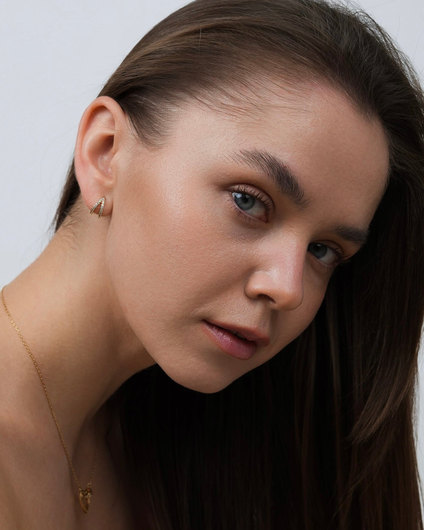 Diana gold-plated pavé huggie earrings worn on model, angled portrait view.