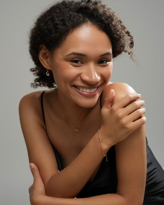 Lifestyle portrait of model wearing Muna gold plated hoop earrings with moon and sun charms