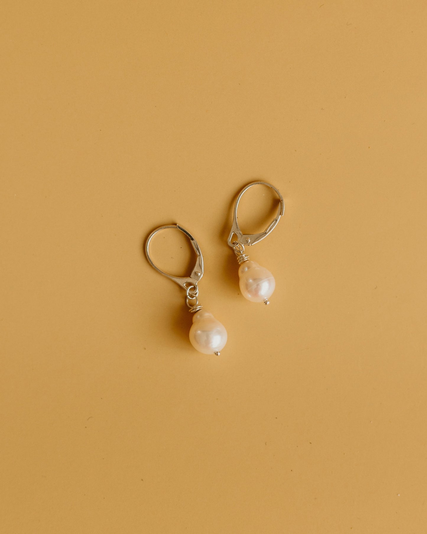 Pair of pearl earrings on a beige background