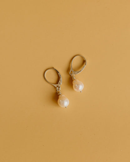 Pair of pearl earrings on a beige background