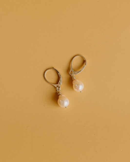 Pair of pearl earrings on a beige background