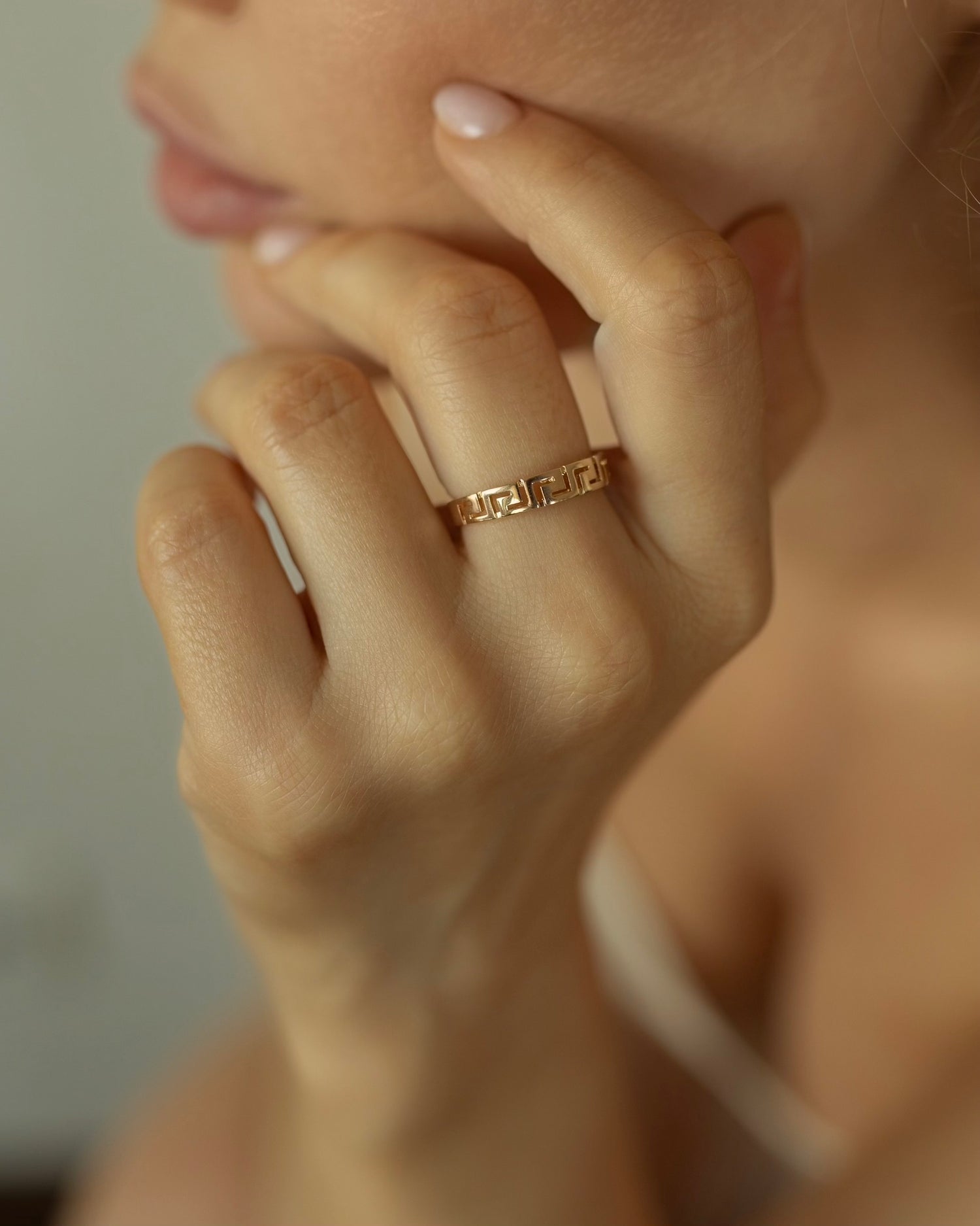 Close-up of a hand wearing a gold ring with a blurred background