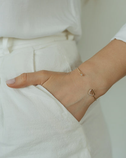 Close-up of a person wearing a delicate bracelet on a plain background