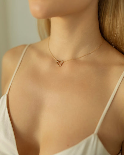 Necklace with a heart pendant worn by a person in a white top.