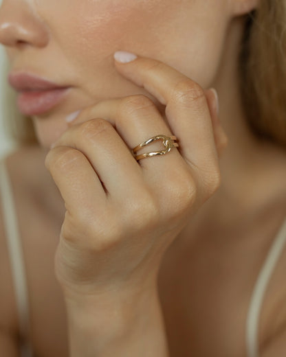 Close-up of a hand wearing a gold ring with a blurred background