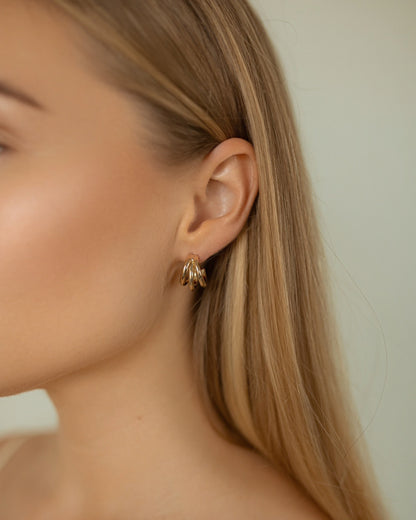 Close-up of a person wearing a gold earring with a blurred background