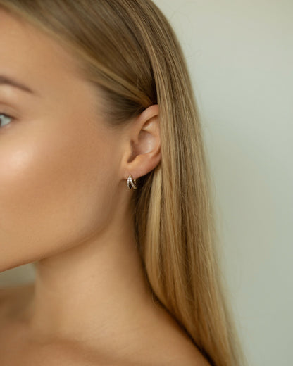 Close-up of a person wearing a delicate earring with a neutral background