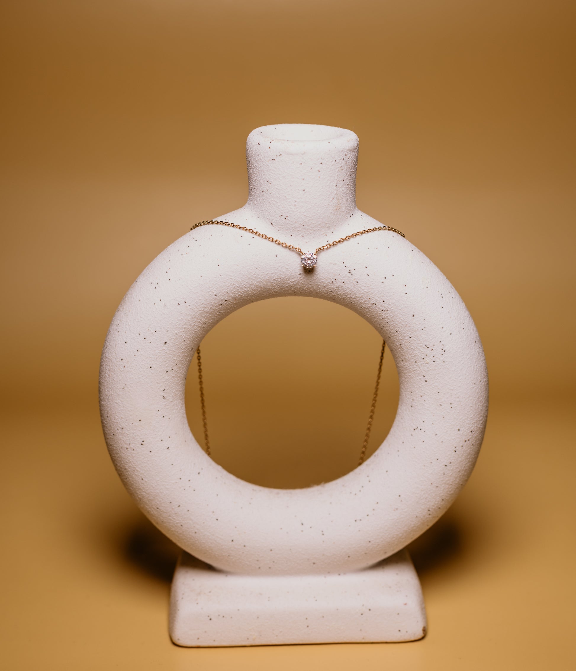 White ceramic ring-shaped vase on a beige background