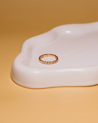 Gold ring with stones on a white ceramic dish with a yellowish-brown background