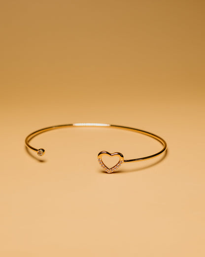 Gold bracelet with a heart-shaped clasp on a beige background