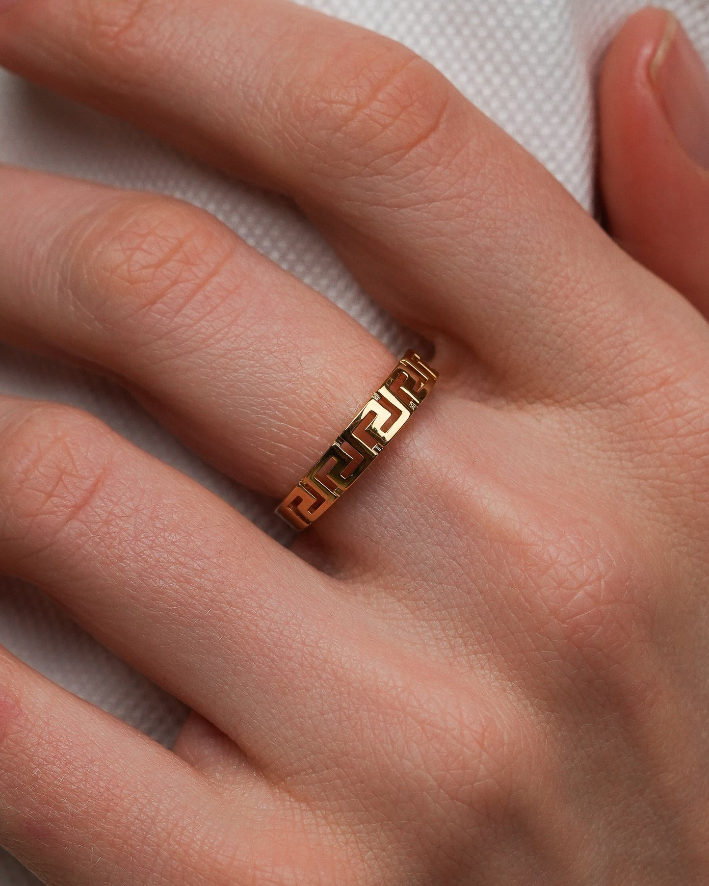 Close-up of a gold-plated ring with geometric pattern worn on a finger