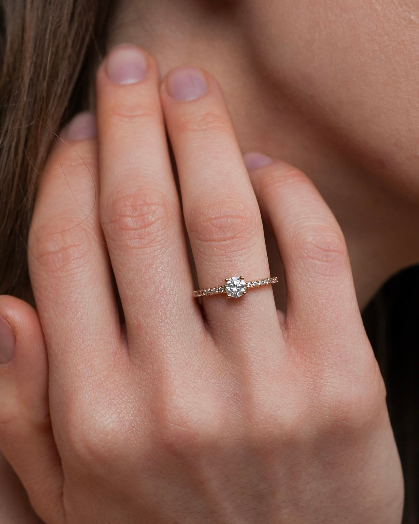 Gold plated solitaire ring with pavé band worn on hand lifestyle portrait