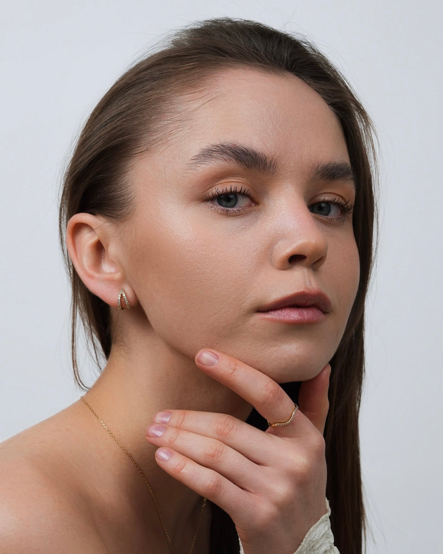 Diana gold-plated pavé huggie earrings worn on model, front portrait view.