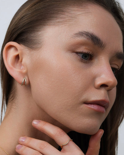 Diana gold-plated pavé huggie earrings worn on model, side profile view.