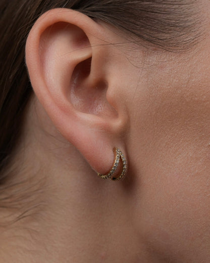 Close-up of Diana gold-plated huggie earrings with pavé stones on ear.