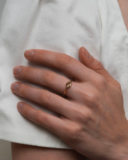 Fira gold knot ring on hand, slim 18k gold plated stacking ring lifestyle image