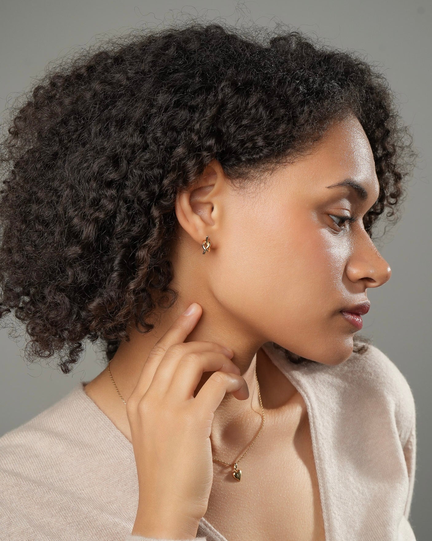 Gold knot stud earrings in 18k gold plating 3 microns worn by model side profile.