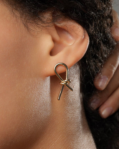 Gold knot stud earrings in 18k gold plating 3 microns worn on ear close-up