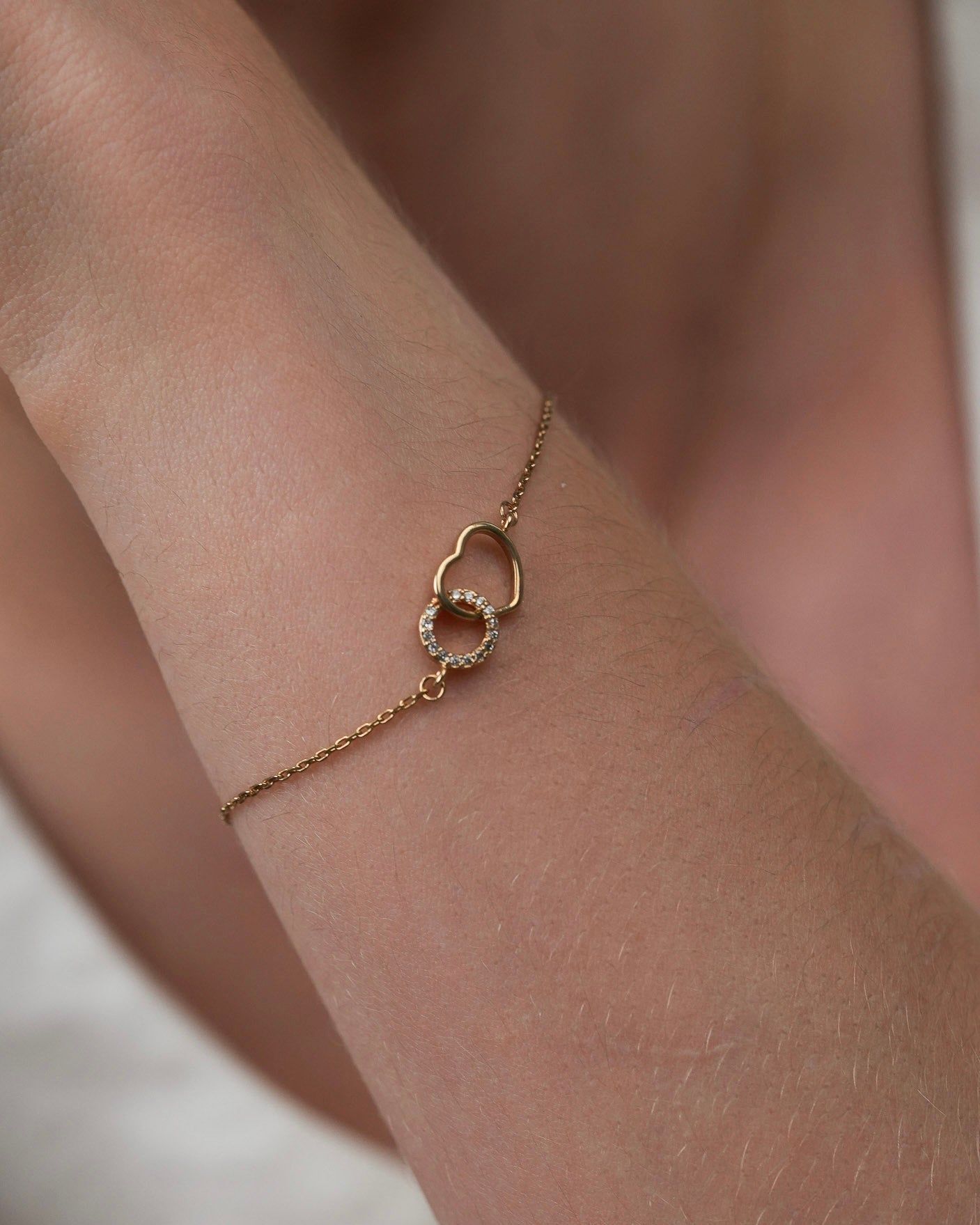 Gold plated heart bracelet with cubic zirconia worn on wrist close-up detail