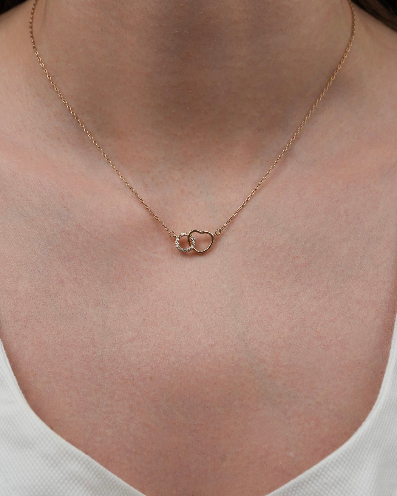 Gold plated heart necklace with cubic zirconia worn on neckline close-up