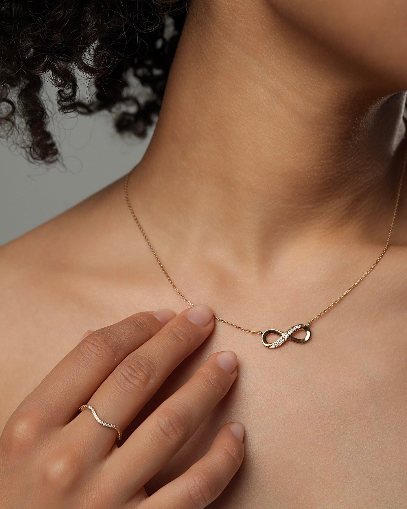 Infinity pendant necklace worn by a model in 18k gold plated finish