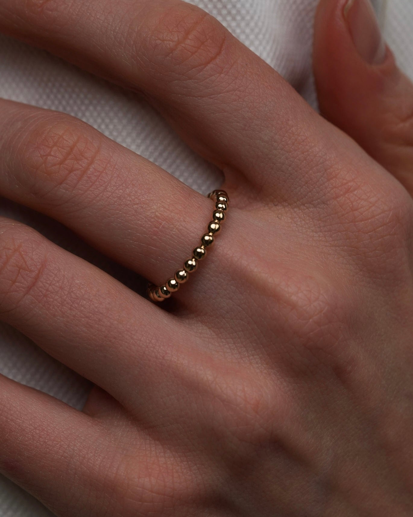 Gold-plated beaded ring worn on finger close-up minimalist jewelry