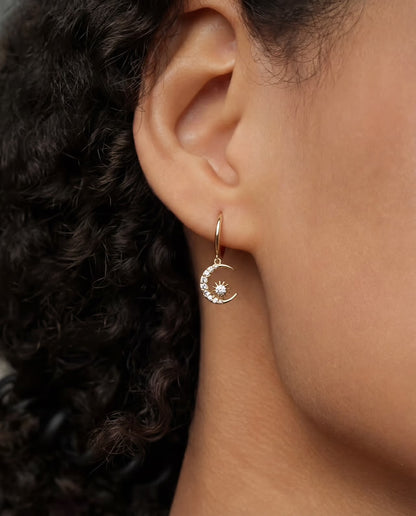 Close-up of Muna gold plated hoop earring with moon charm and cubic zirconia worn on ear