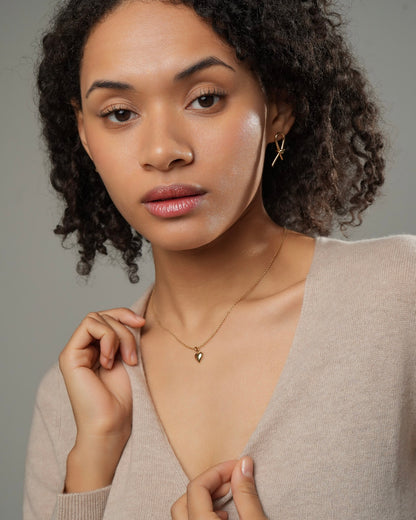 Delicate small gold heart necklace in 18K gold plating, polished pendant worn as everyday jewelry.