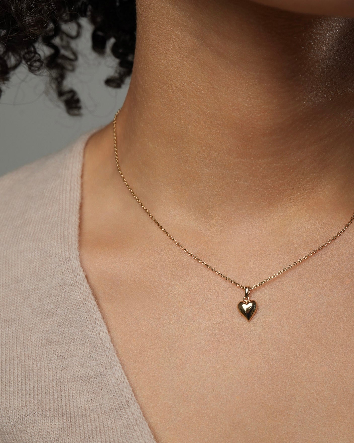 Small gold heart necklace worn on model, 18K gold plated heart pendant resting at collarbone.