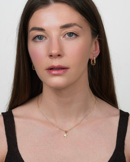 Gold star pendant necklace with cubic zirconia on model