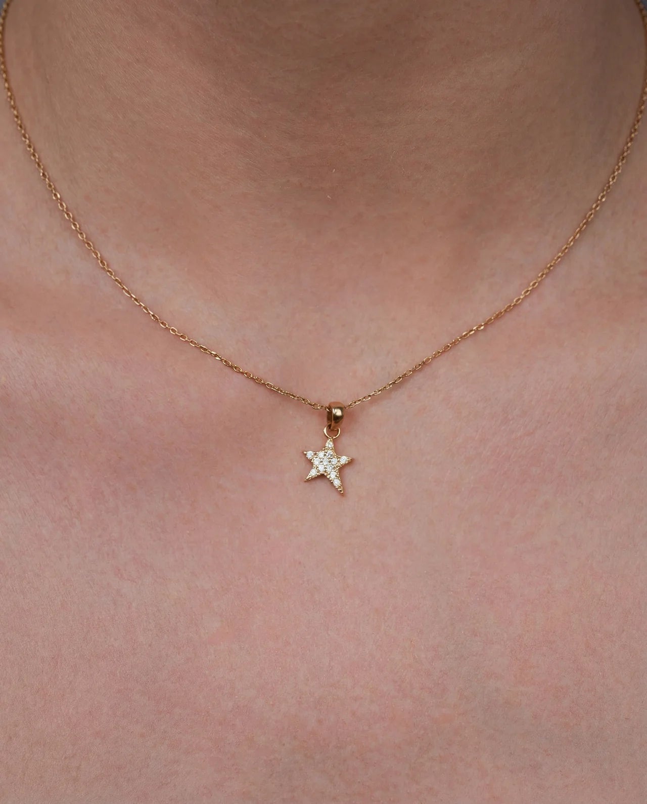 Gold star necklace with cubic zirconia worn on neck
