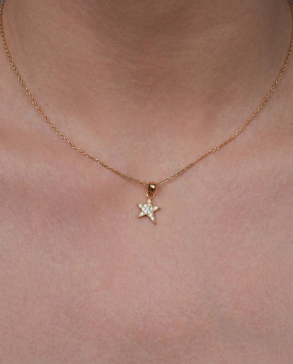 Gold star necklace with cubic zirconia worn on neck