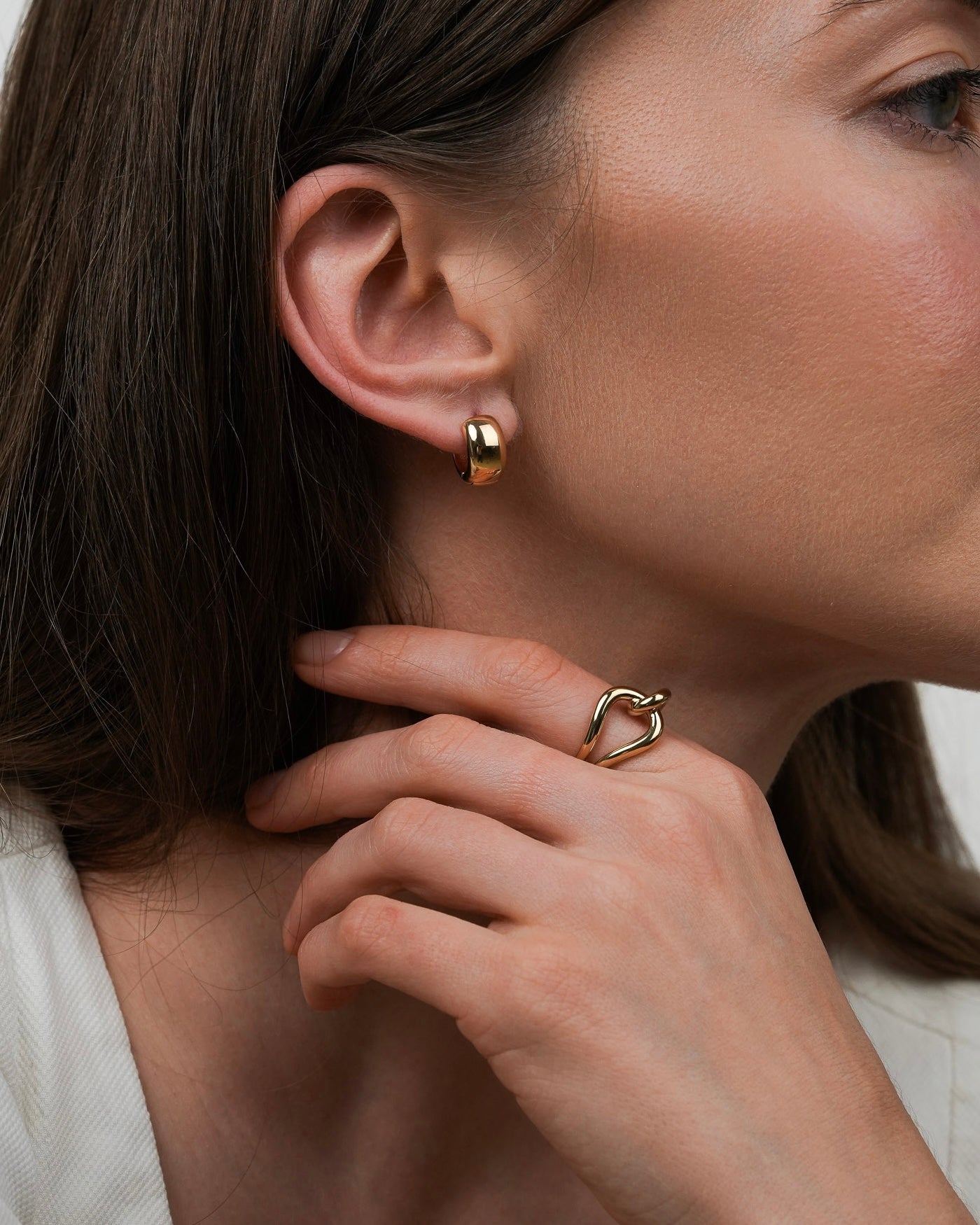 Gold-plated sculptural ring paired with a minimalist gold earring on model