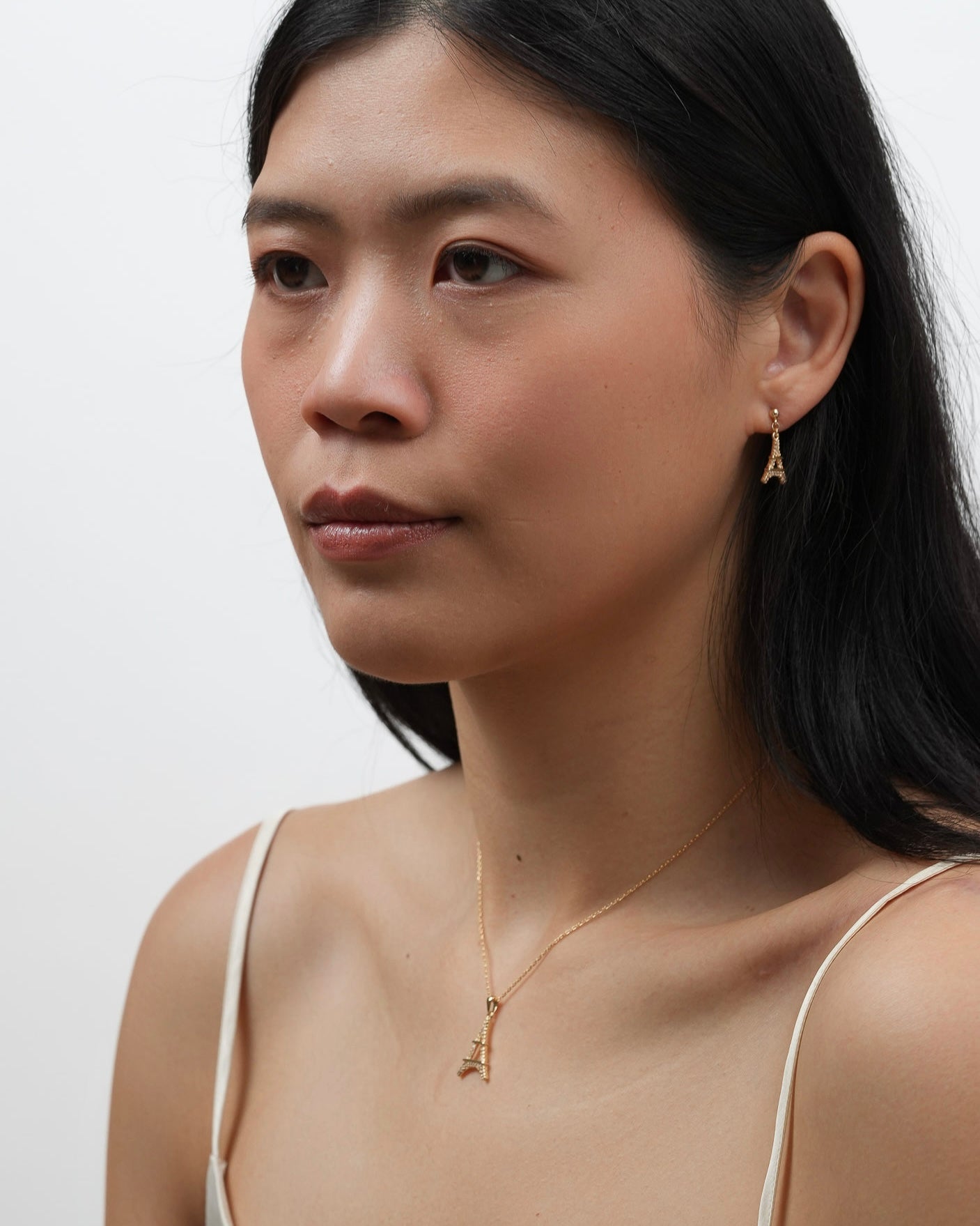 Model wearing gold plated Eiffel Tower dangle earrings with matching necklace